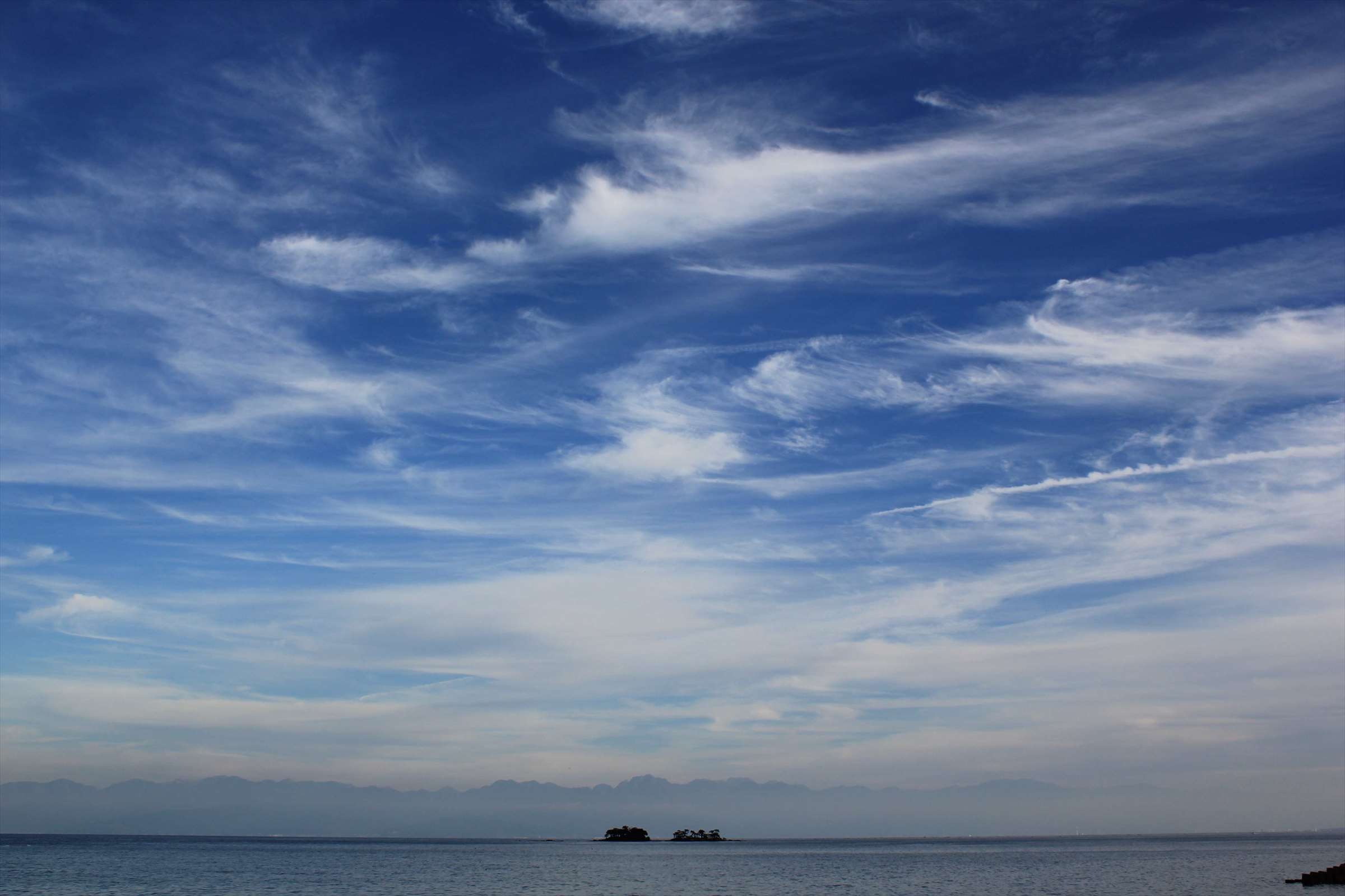 青空に広がる筋雲と穏やかな富山湾