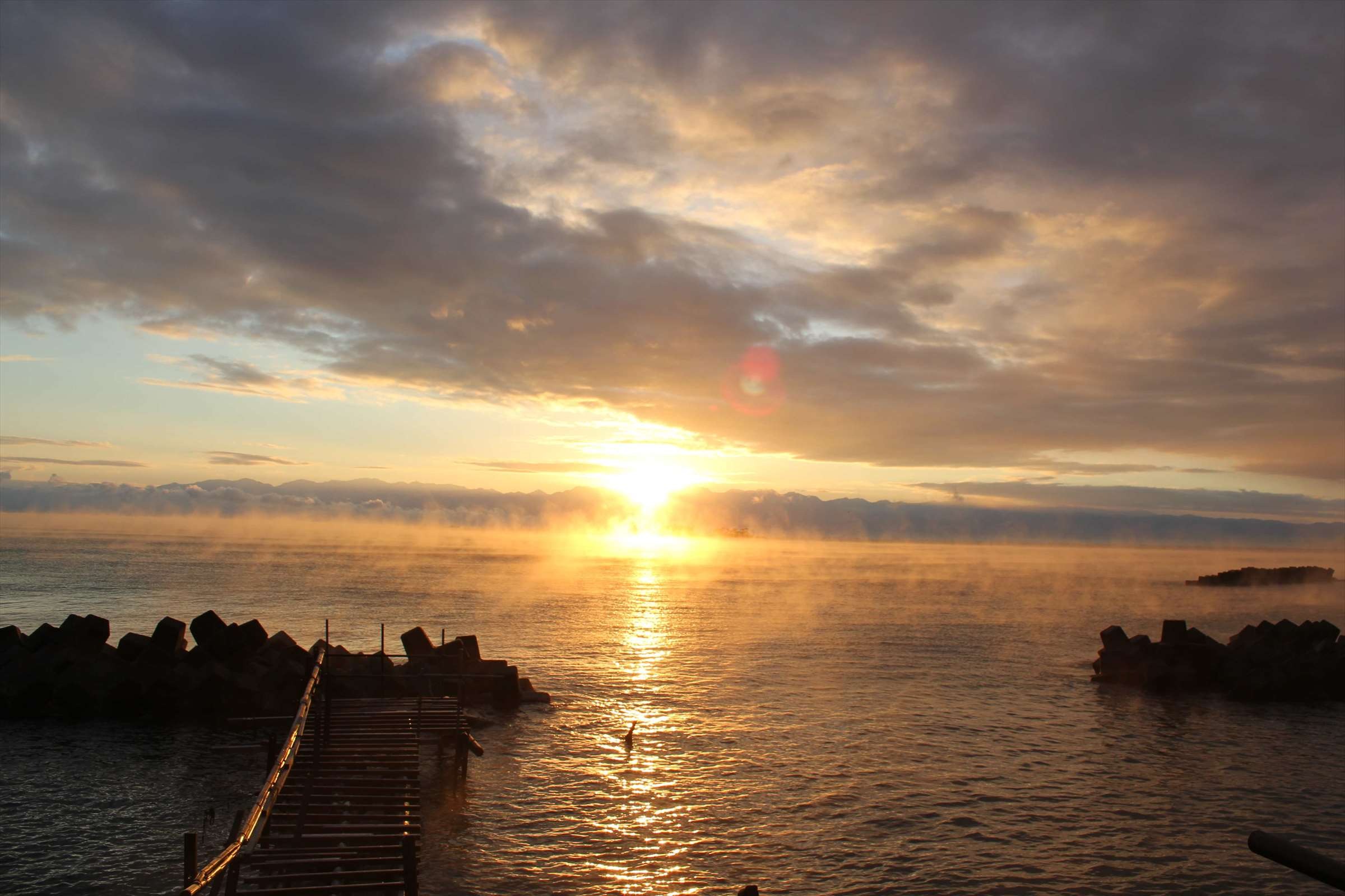 朝日が昇る富山湾、桟橋と霧立ち込める海面