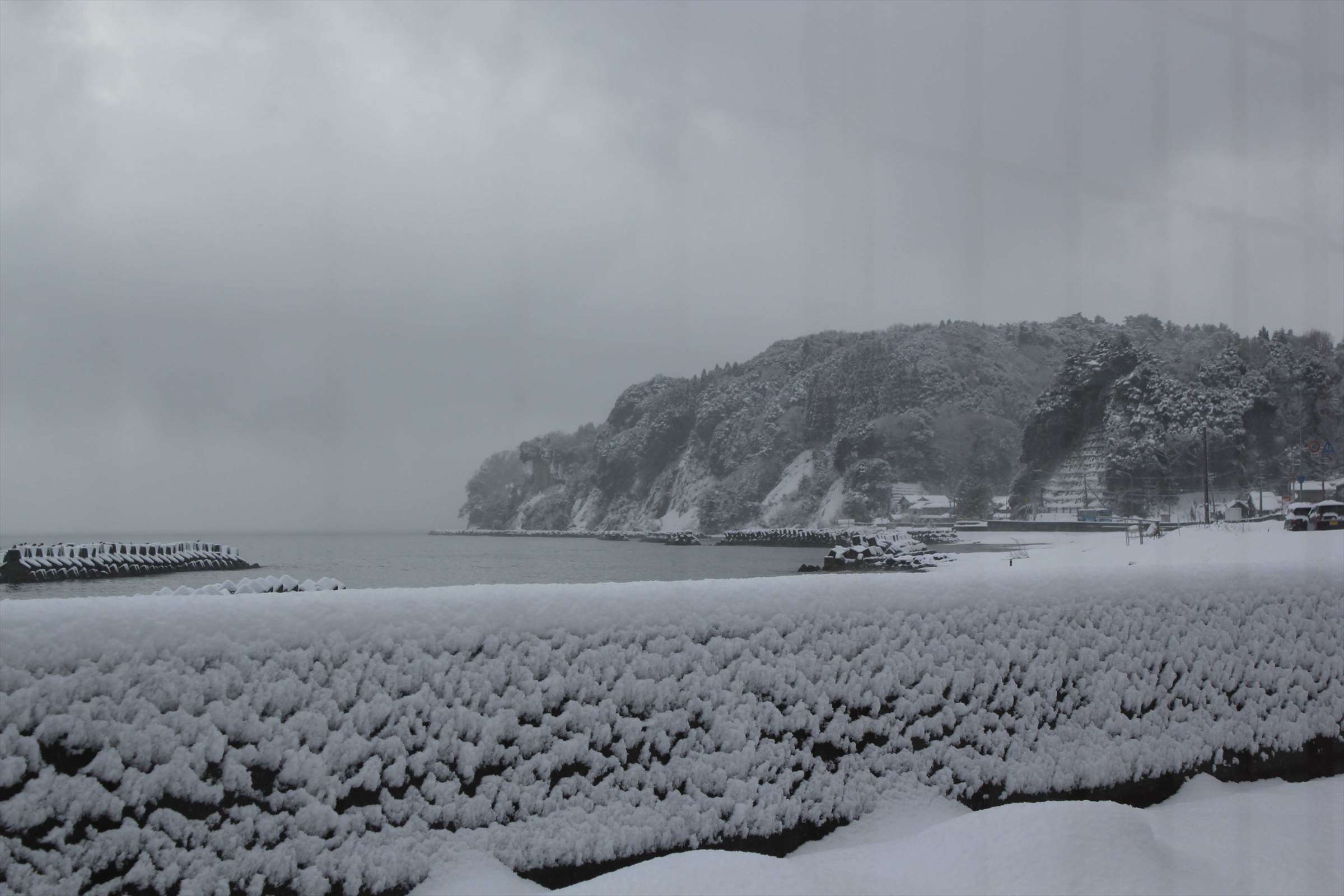 雪に覆われた浜辺と崖、冬の富山湾の海岸