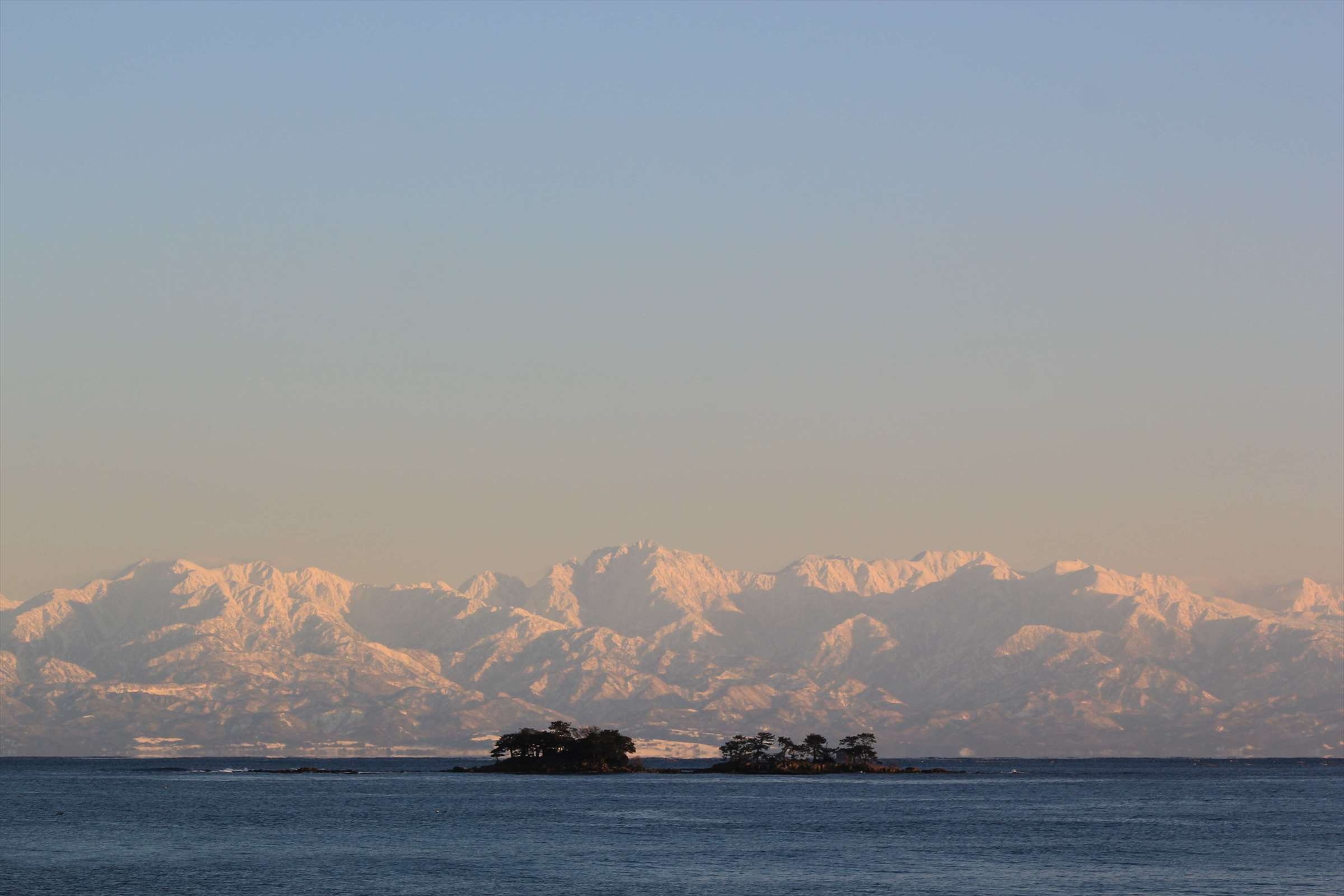 朝焼けに染まる立山連峰と小島のシルエット