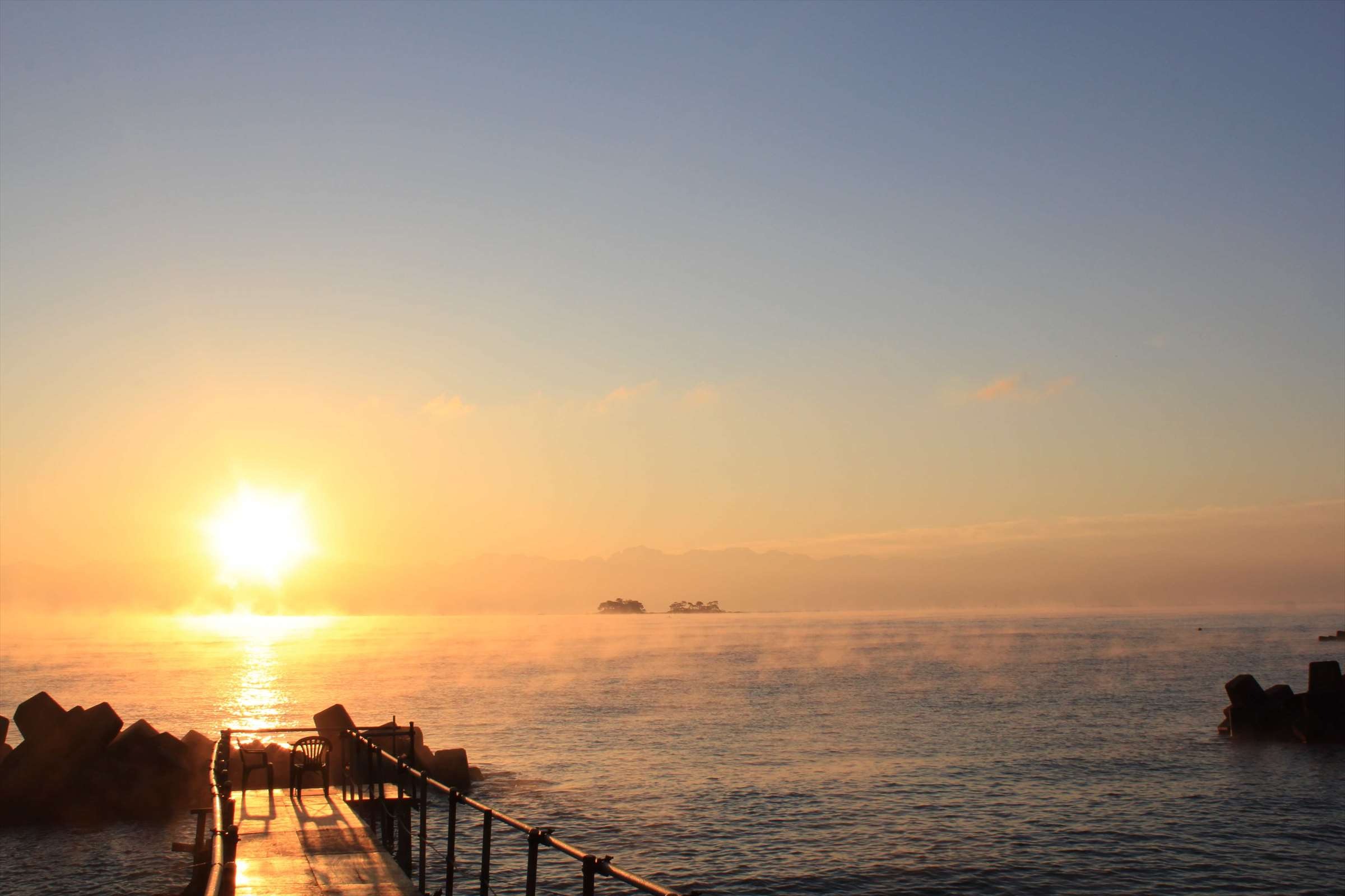 朝日が昇る富山湾、桟橋と霧の中の小島