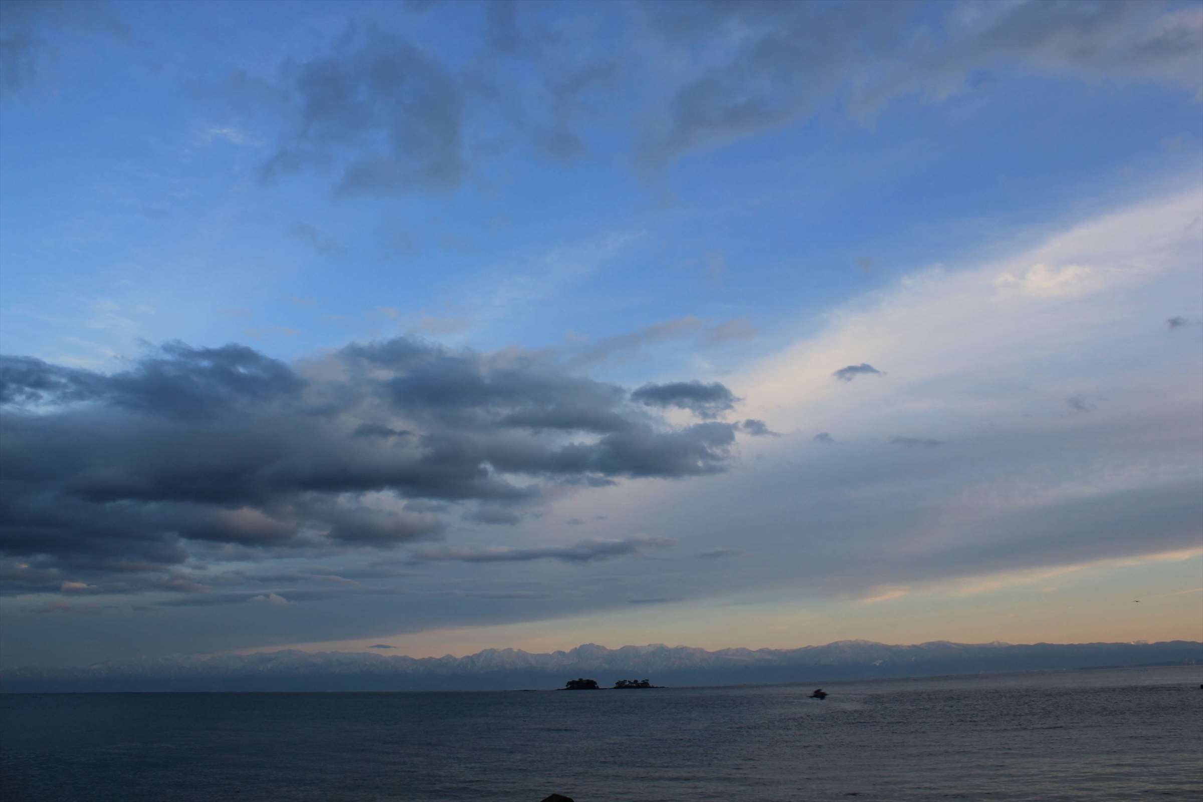 夕暮れの富山湾と立山連峰、流れる雲と小島