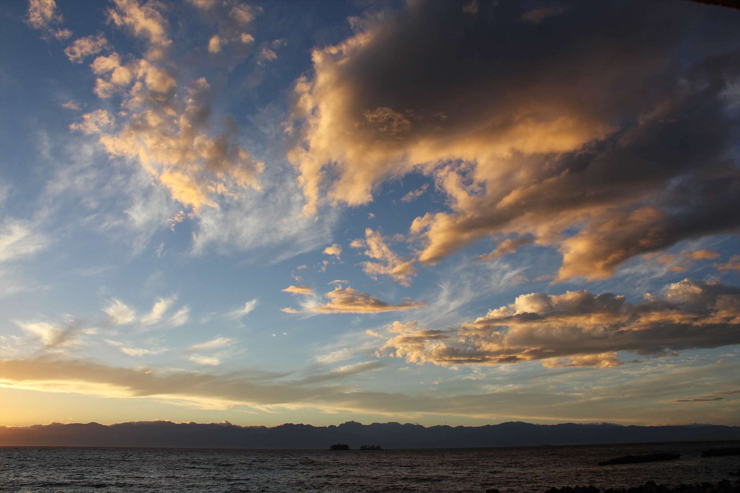 夕焼けの雲と富山湾、立山連峰と小島のシルエット