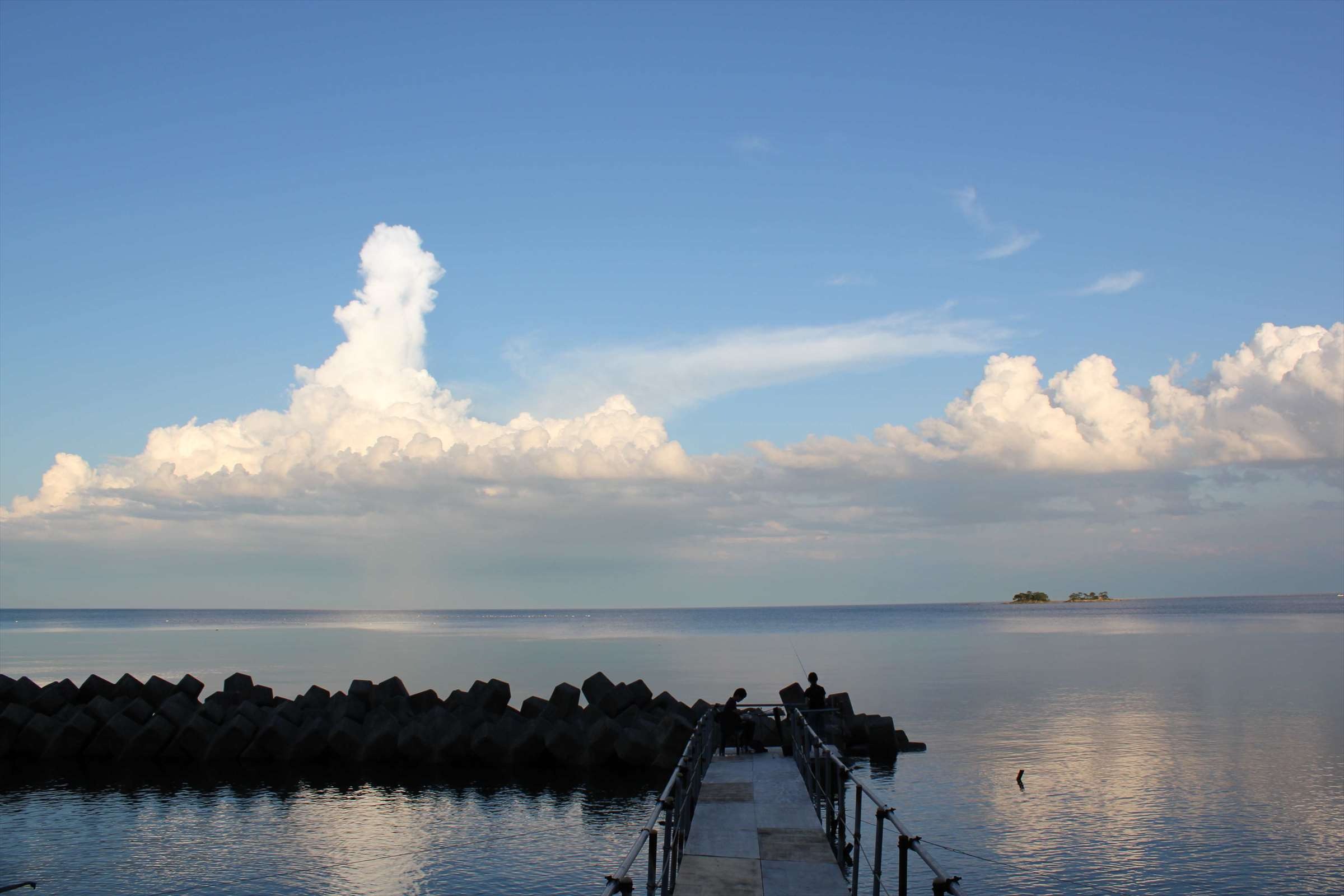 夏の積乱雲が広がる富山湾、桟橋と小島