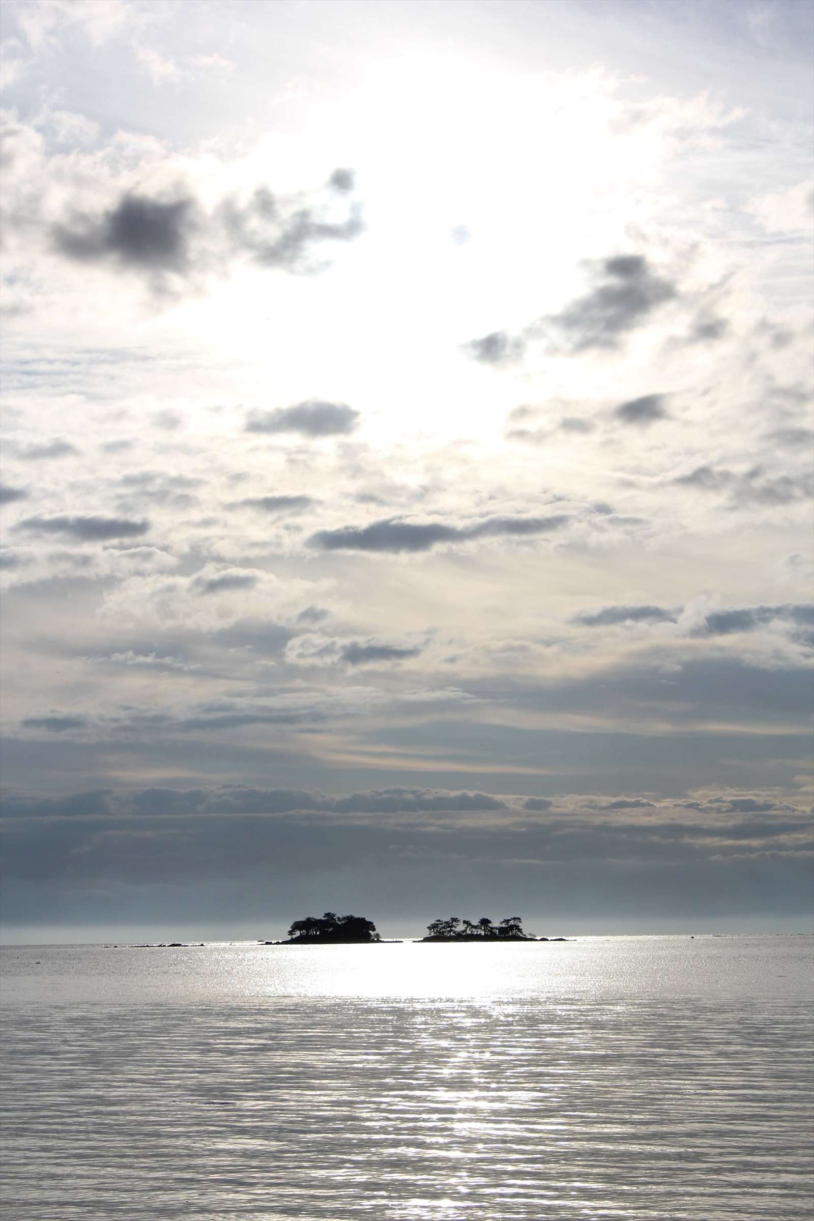 銀色に輝く海面と二つの小島のシルエット