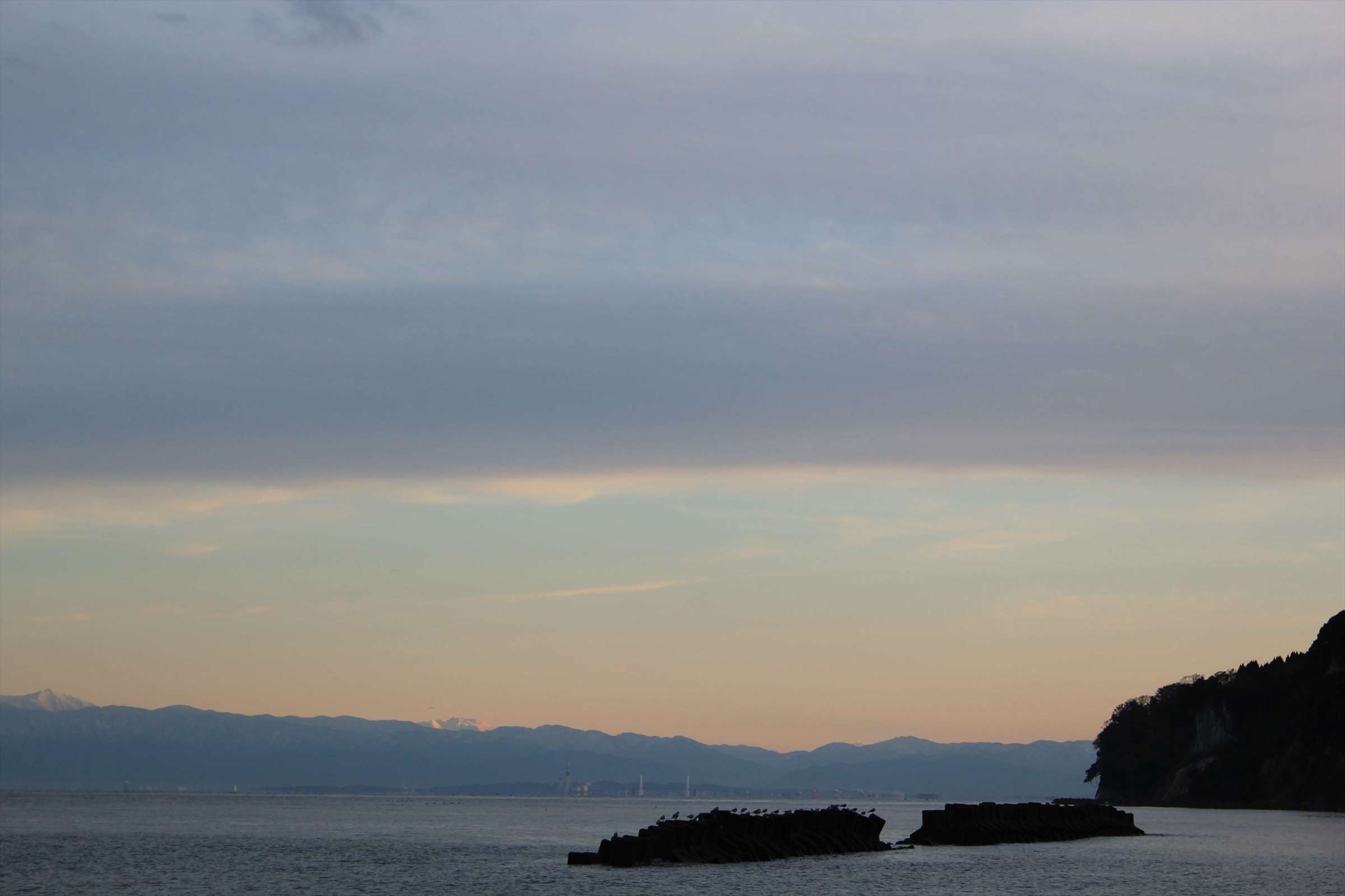 夕暮れの富山湾、テトラポッドと岬のシルエット
