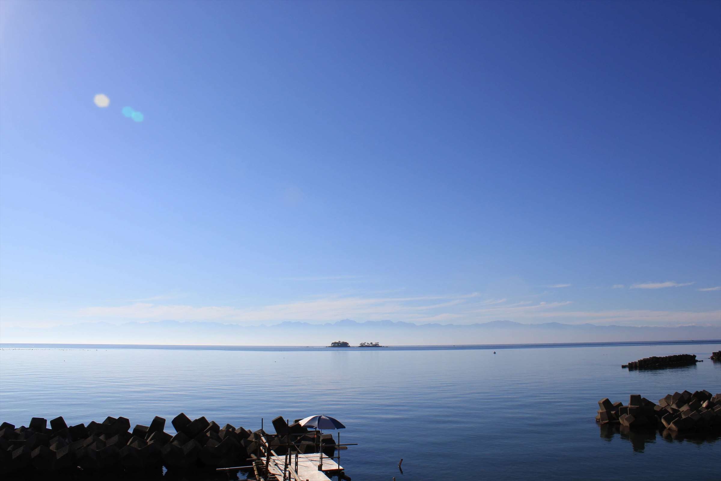 快晴の青空と穏やかな富山湾、桟橋と小島