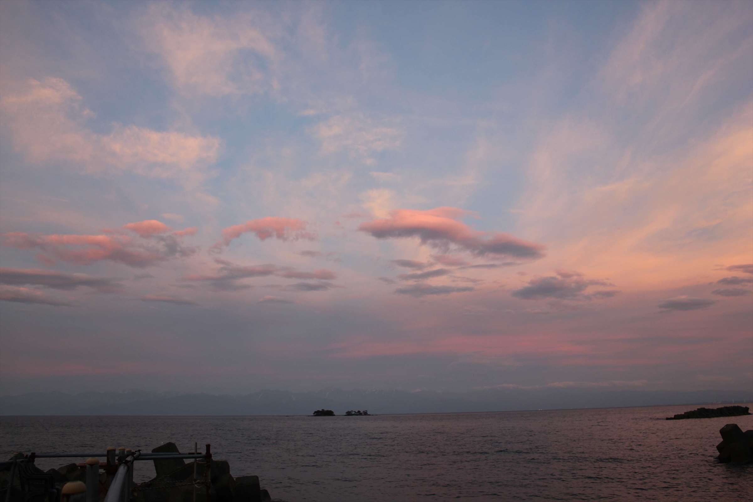 夕暮れにピンク色に染まった雲と富山湾
