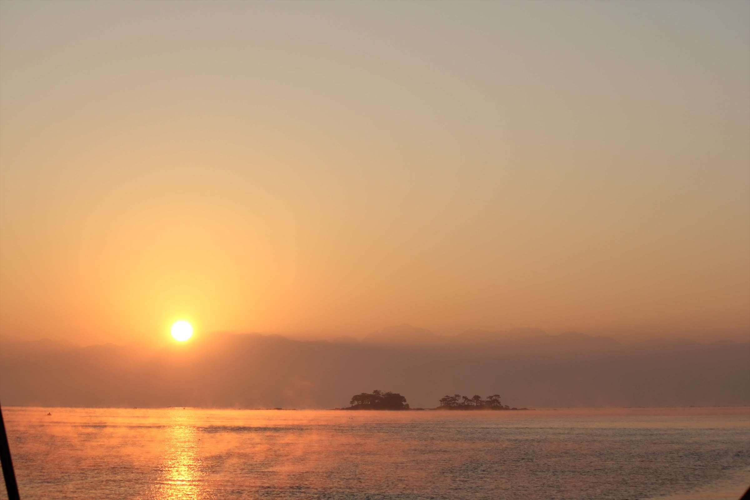 朝焼けの富山湾、小島と金色に輝く海面