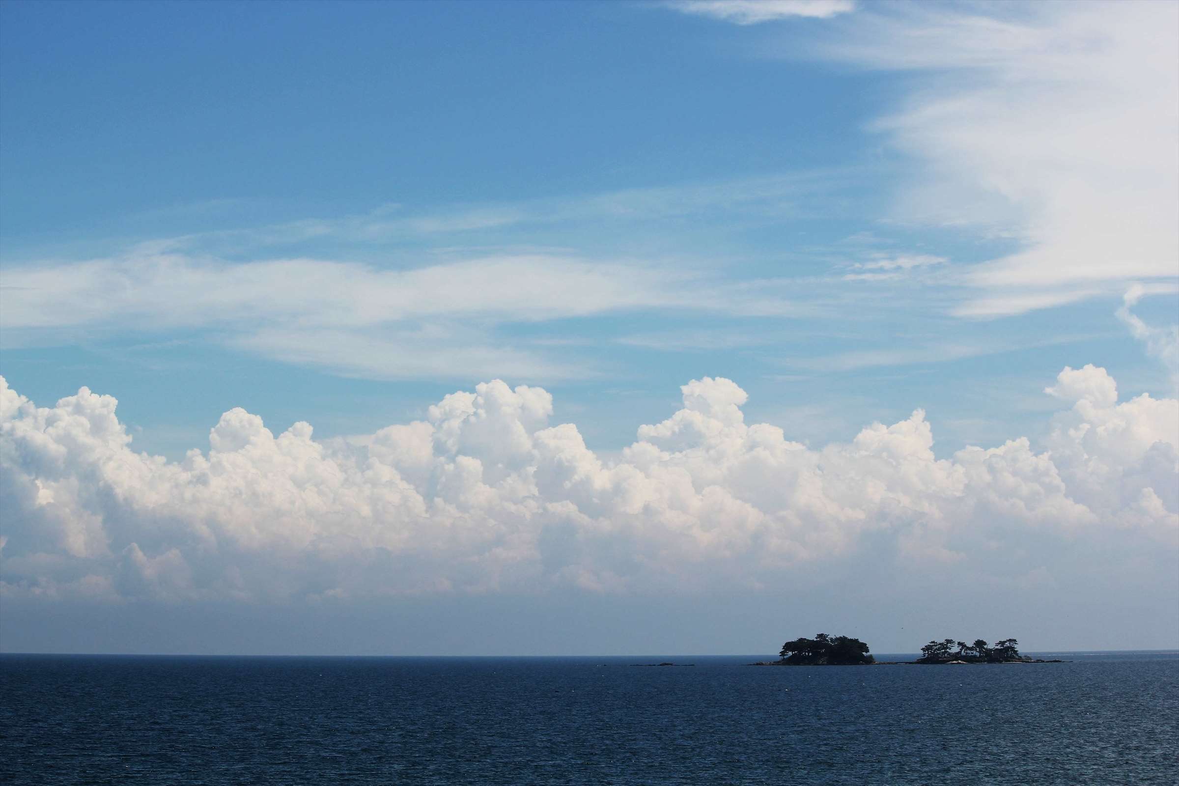 夏の青空と入道雲、富山湾に浮かぶ小島