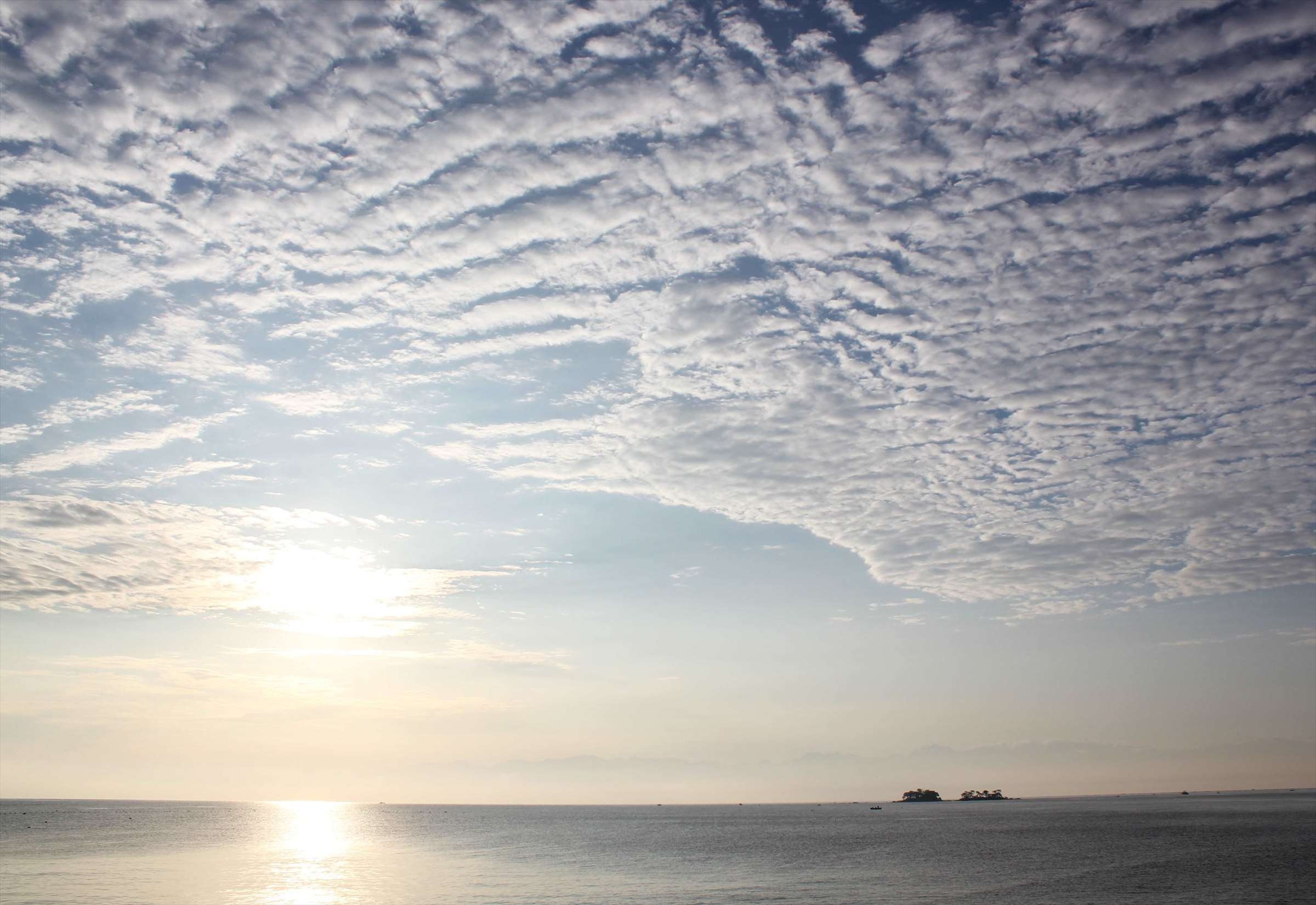 うろこ雲と光る海面、小島が浮かぶ富山湾の朝