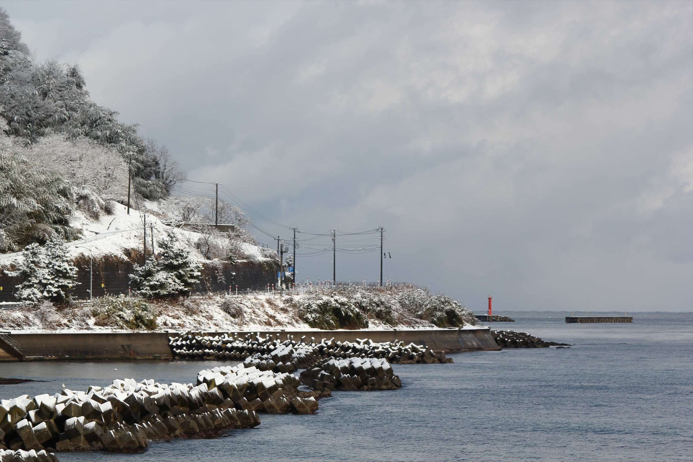 雪景色の海岸沿いの道路と赤い灯台