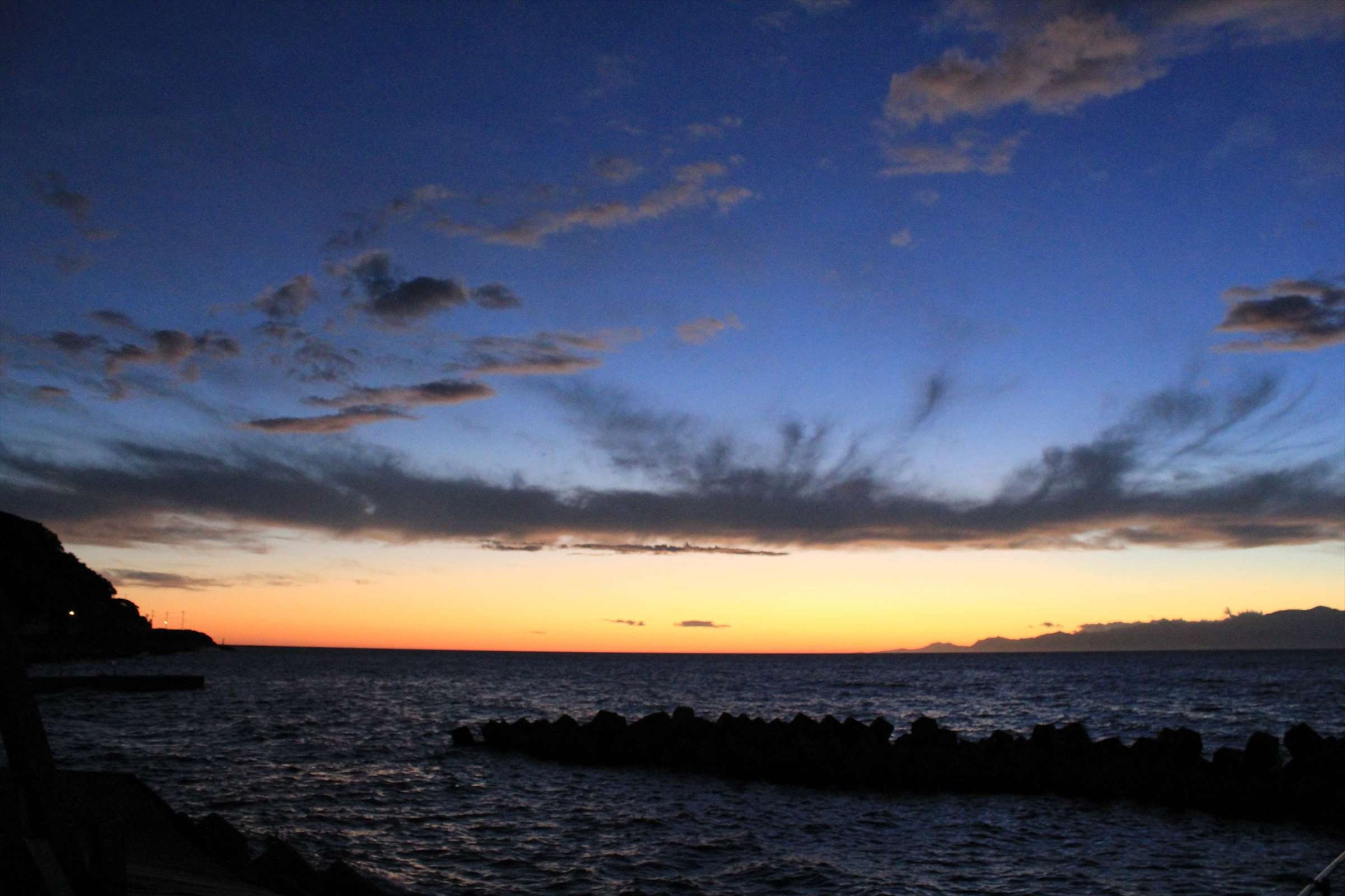 夜明け前の水平線の朝焼けとテトラポッドの富山湾